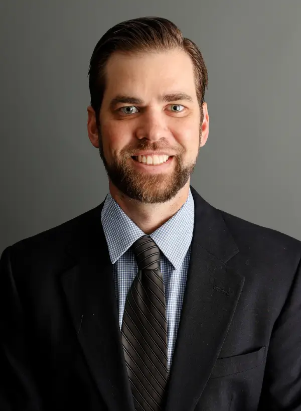 A man in a suit and tie smiling for the camera.